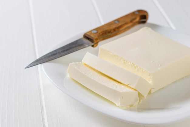 Un couteau avec un manche en bois à côté d&#39;un morceau de fromage serbe en tranches.