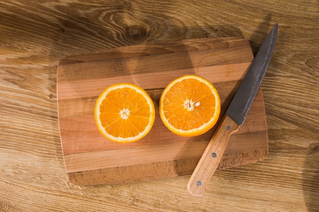 Un couteau et une orange sur une table en bois
