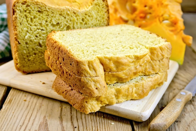 Un couteau à pain à la citrouille fait maison coupe la citrouille jaune sur un fond de planches de bois