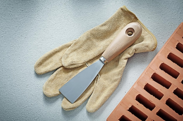 Couteau à palette de gants de protection en briques orange sur fond de béton concept de maçonnerie