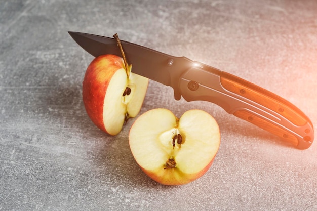 Photo couteau pliant pour la survie et deux moitiés de pomme coupée