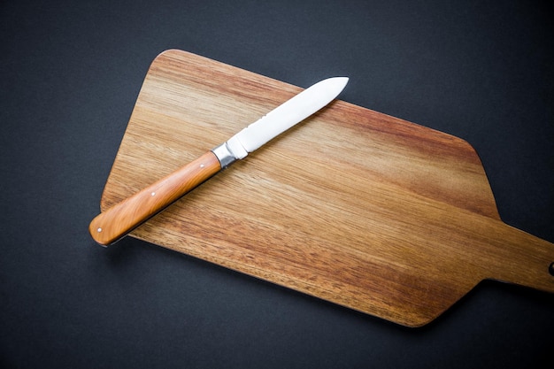 Couteau de poche traditionnel sur une planche à découper en bois Fond noir