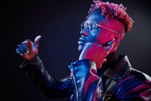 Écouter de la musique Éclairage néon futuriste Jeune homme afro-américain dans le studio