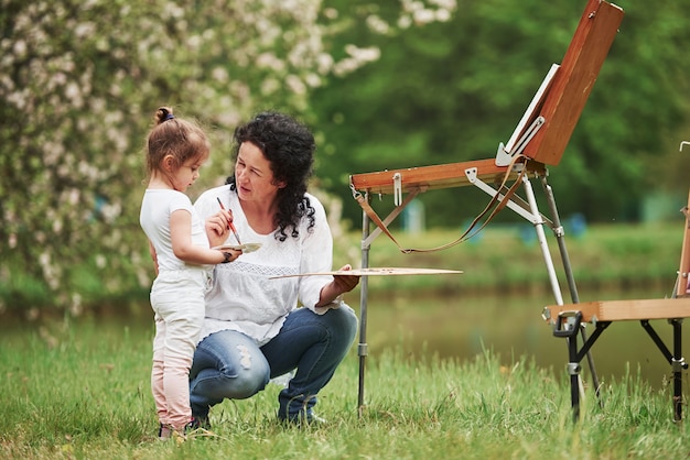 Écoutez attentivement. Enseigner à sa petite-fille à peindre. Dans le parc naturel