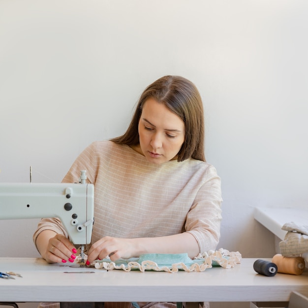 Couturière concentrée cousant des vêtements dans son propre atelier de mode