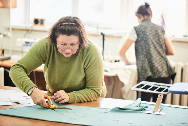 La couturière coupe les ciseaux de tissu sur la table