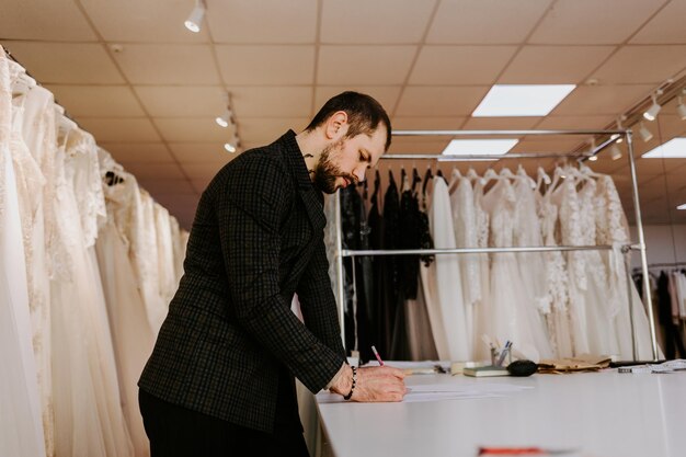 La couturière crée un croquis dans le cahier de travail le concepteur dessine les vêtements et les sacs