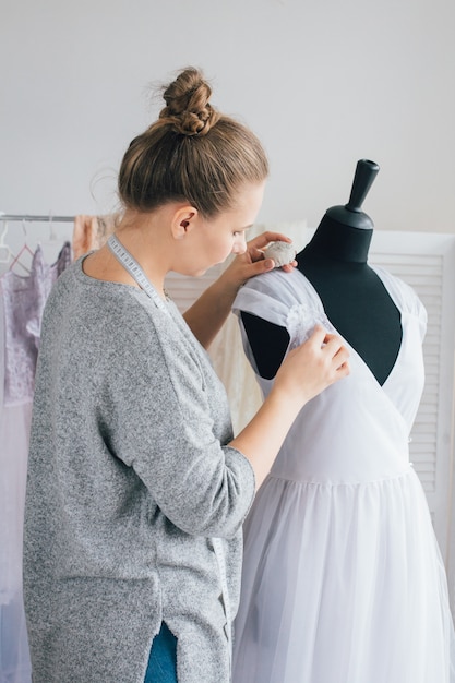 Couturière fait une robe ajustée sur le mannequin