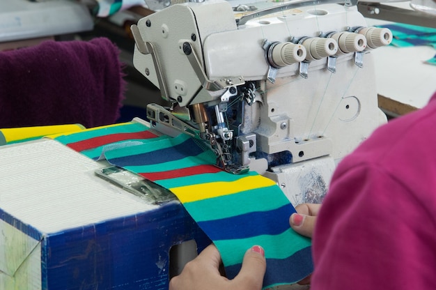 La couturière en gros plan sur la machine coud des vêtements dans une usine de confection