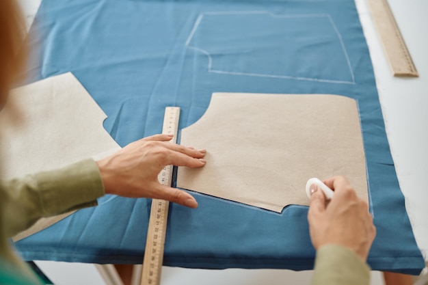 La couturière mesure le tissu sur la table en atelier