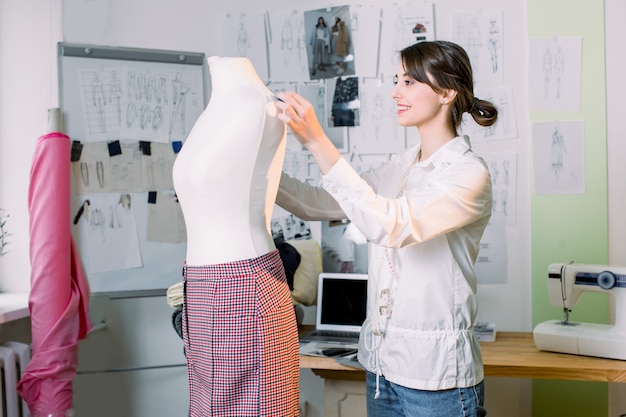 Couturière travaillant sur un nouveau modèle de couture pantalon sur mannequin en studio. Concept de mesure de mannequin de conception de mode.