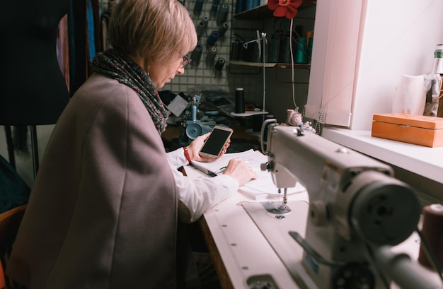 Une couturière utilisant un téléphone portable tout en travaillant dans un atelier. petite entreprise