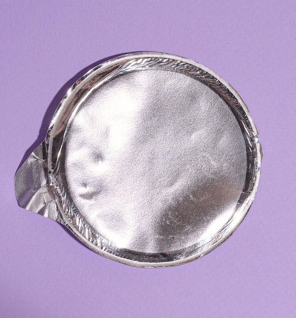 Couvercle rond en aluminium sous l'emballage avec puces sur fond violet à plat