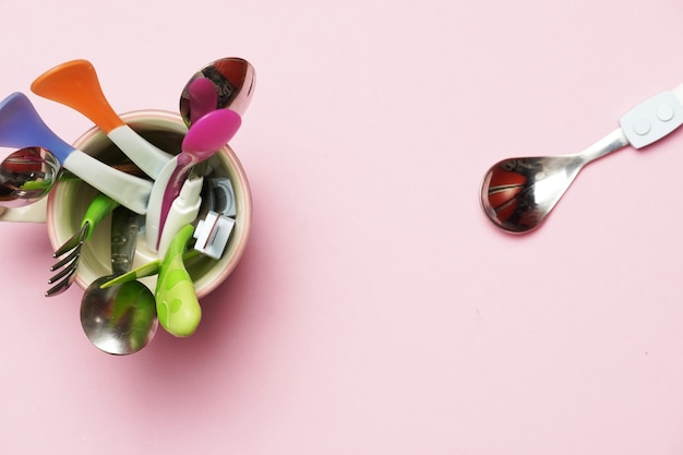 Couverts familiaux dans une tasse après avoir été lavés. Fond rose. conception à plat