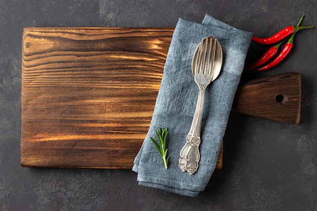 Couverts métalliques avec une serviette sur une planche de bois