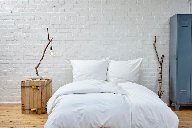 Une couverture blanche sur le lit contre le mur à la maison.