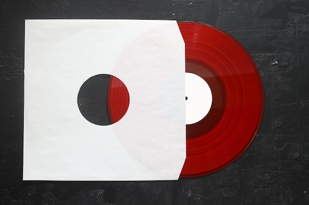 Couverture en papier blanc vieilli et disque LP en vinyle rouge isolé sur fond noir