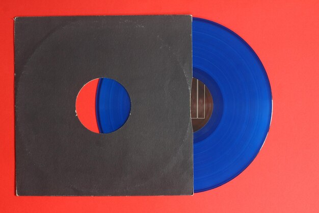 Photo couverture en papier noir vieilli et disque lp en vinyle bleu isolé sur fond rouge