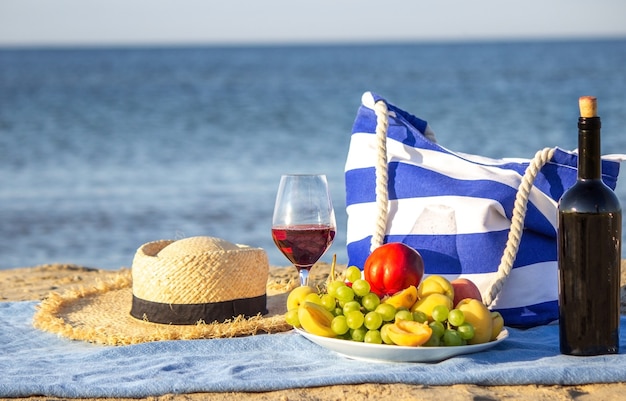 Couverture de pique-nique, vin, fruits, belle plage de la mer. Mise au point sélective