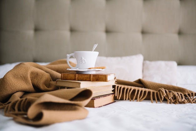 Couverture près des livres et tasse blanche