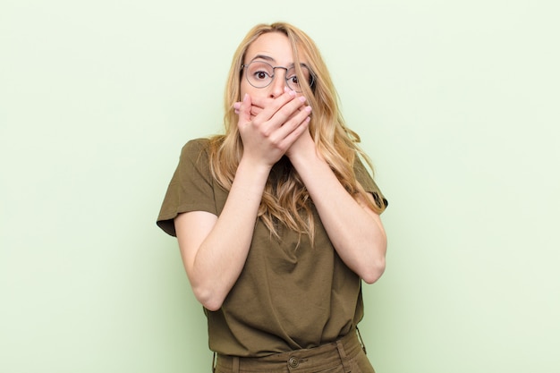 couvrant la bouche avec les mains avec une expression choquée et surprise, en gardant un secret ou en disant oups