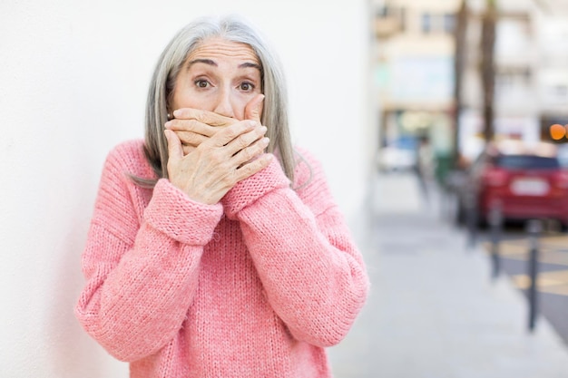 couvrant la bouche avec les mains avec une expression de surprise choquée en gardant un secret ou en disant oups