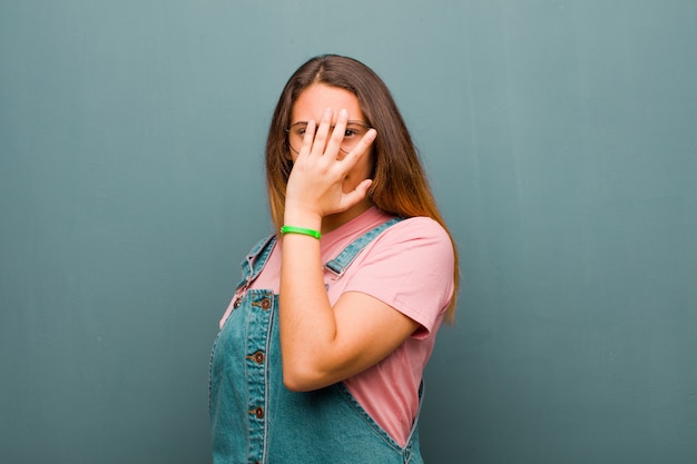 couvrant le visage avec les mains, jetant un coup d'œil entre les doigts avec une expression surprise et regardant sur le côté