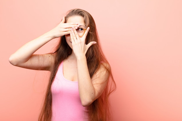 couvrant le visage avec les mains, jetant un coup d'œil entre les doigts avec une expression surprise et regardant sur le côté