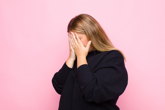 couvrant les yeux avec les mains avec un air triste et frustré de désespoir, pleurant, vue latérale