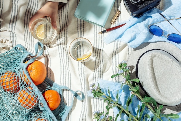 Couvre-plat de pique-nique d'été féminin, fruits, baies et eau de citron sur une couverture en coton à rayures