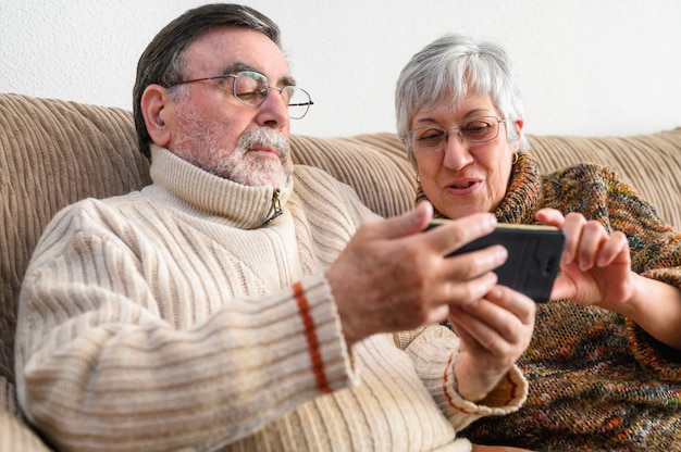 Covid-19 reste à la maison. Heureux couple de retraités, faisant un appel vidéo familial avec téléphone portable. Distanciation sociale, expression positive.