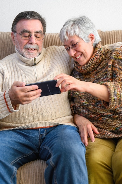 Covid-19 reste à la maison. Heureux couple de retraités, faisant un appel vidéo familial avec téléphone portable. Distanciation sociale, expression positive.