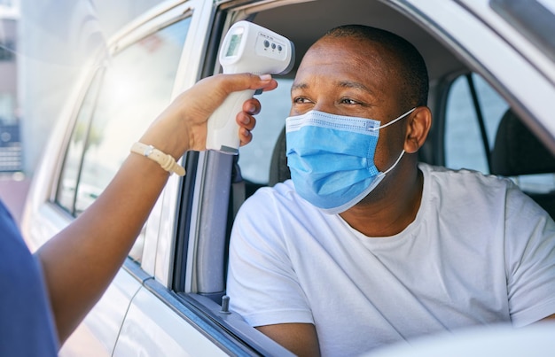 Covid corona et site de test d'infection en tant que station-service au volant pour les personnes voyageant un homme africain portant un masque protecteur pour éviter l'infection et arrêter la propagation en conduisant sa voiture