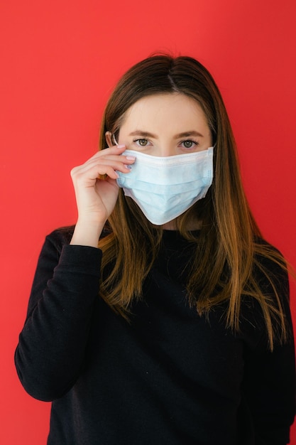COVID19 Pandemic Coronavirus Jeune fille sur fond rouge dans un masque protecteur