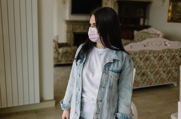 COVID19 Pandémie Coronavirus Femme isolement à domicile quarantaine automatique portant un masque protecteur contre la propagation du virus de la maladie SARSCoV2 Masque d'isolement fille sur le visage contre la maladie à coronavirus 2019