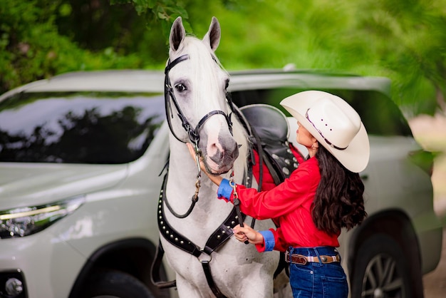 cow-girl souriant en marchant à côté de son cheval blanc