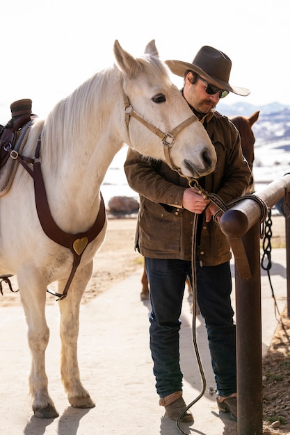 Photo cowboy attachant son cheval