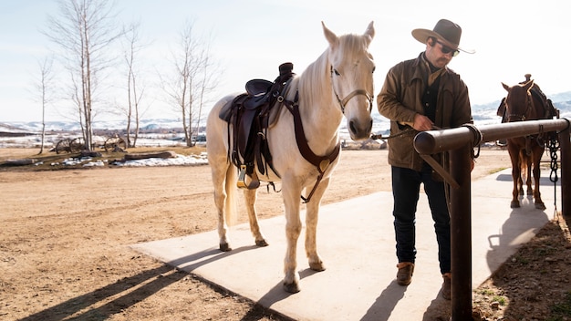 Photo cowboy attachant son cheval