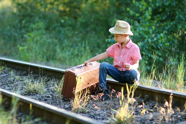 Cowboy garçon avec valise et concept de voyage occidental de chemin de fer