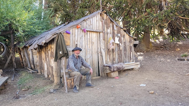 Cowboy Gaucho est assis en face d'une cabane en bois avec un signe qui dit "le mot dessus