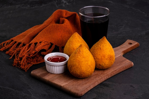 Coxinha frite traditionnelle farcie de poulet et un verre de soda froid.