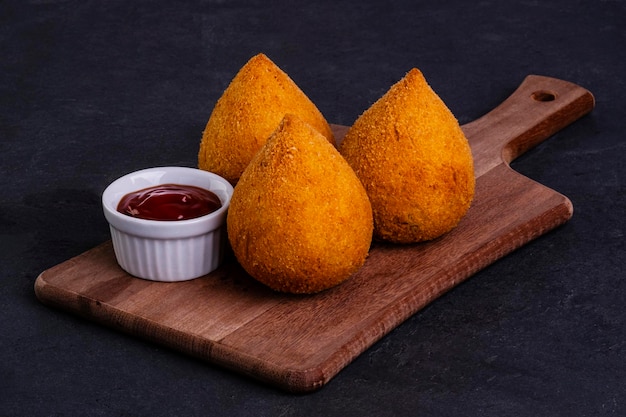 Coxinha frite traditionnelle sur une planche en bois sur ardoise.