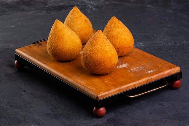 Coxinha frite traditionnelle sur une planche en bois sur ardoise.