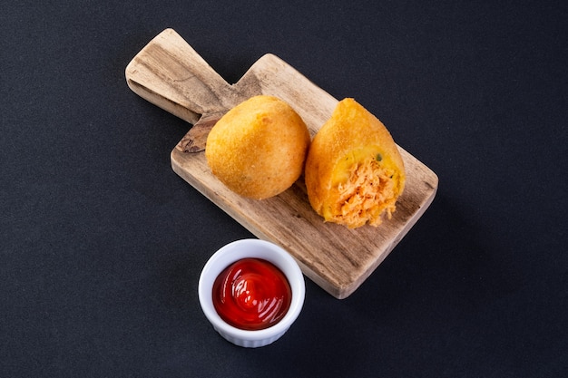 Coxinha sur planche de bois avec fond noir.