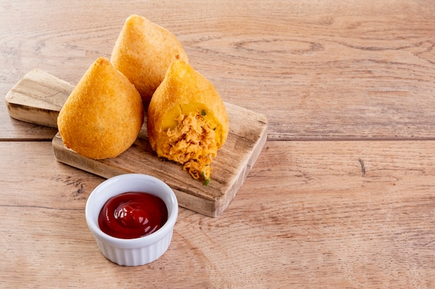 Coxinha sur une planche à découper sur une table en bois.