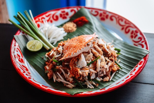 Crab Pad Thai servi avec du citron vert, des oignons verts, des germes de soja. cacahuète écrasée et poudre de chili.