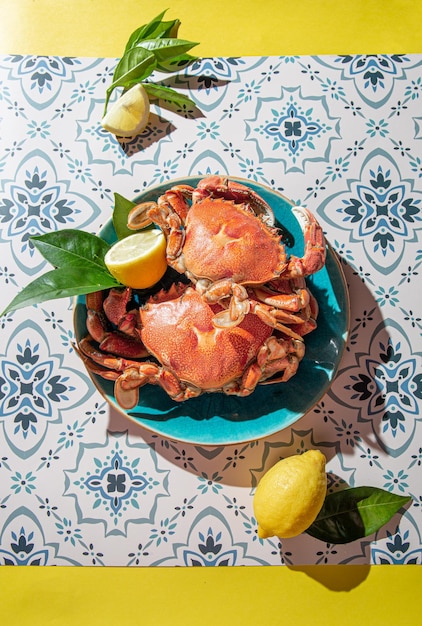 Crabe cuit sur plaque bleue citrons vin rosé sur table immitation du soleil