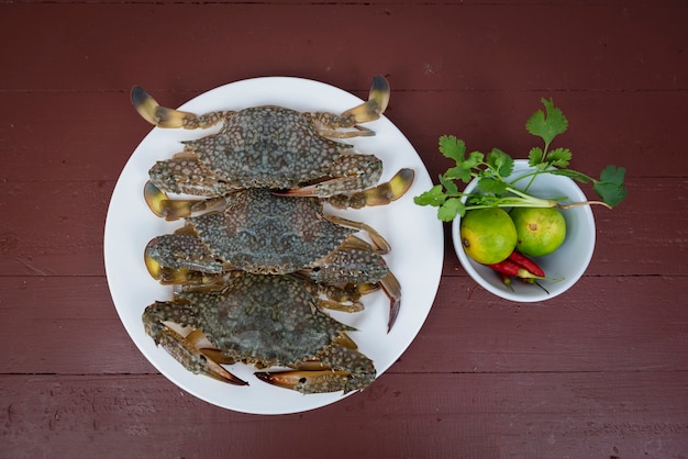 Crabes bleus citron et épices sur plaque, sur un fond en bois