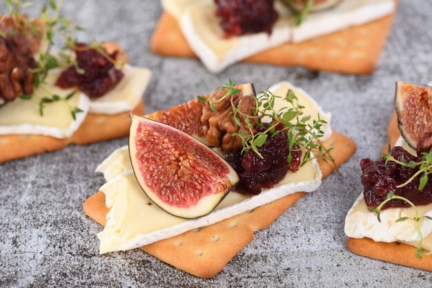 Cracker avec une tranche de camembert, de confiture, de figues et de noix. Une excellente idée de collation pour des vacances, un pique-nique ou une fête.