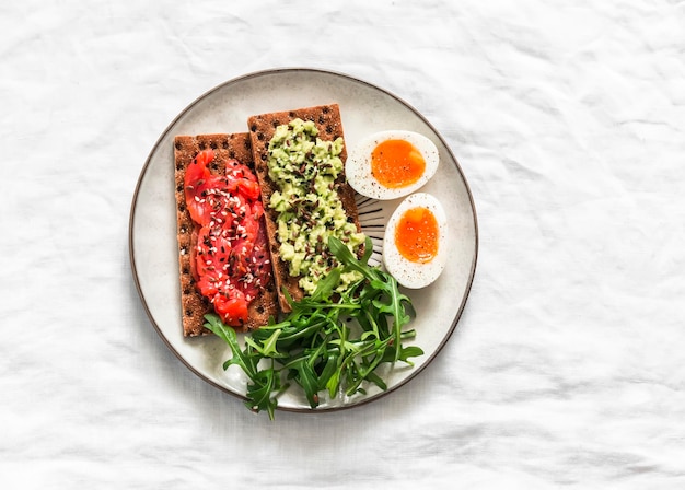 Crackers de seigle avec avocado et saumon œufs bouillis rogues délicieuse collation de petit déjeuner sur un fond clair vue de haut